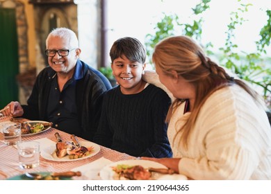 Happy Latin Grand Parents Enjoy Lunch With Grandchild At Home On Patio