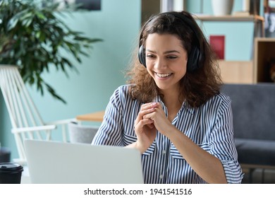 Happy latin hispanic girl college student wearing headphones watching distance online class, remote university webinar or having talk on laptop video conference call virtual meeting at home or campus. - Shutterstock ID 1941541516