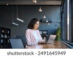 Happy latin hispanic young business woman working on laptop computer in company office. Smiling Indian entrepreneur manager businesswoman using pc for communication, learning at workplace. Copy space