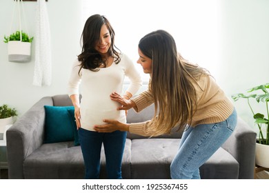 Happy latin midwife caressing the belly of a pregnant woman. Female best friend touching the stomach of her pregnant friend