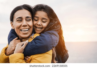 Happy latin mother and daughter having fun together during winter time - Mom day concept - Focus on girl face - Powered by Shutterstock