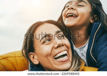 Happy latin mother and daughter having fun during winter time - Main focus on girl nose
