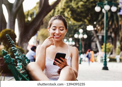 Happy Latin woman using mobile phone in latin america, mexican girl in Mexico