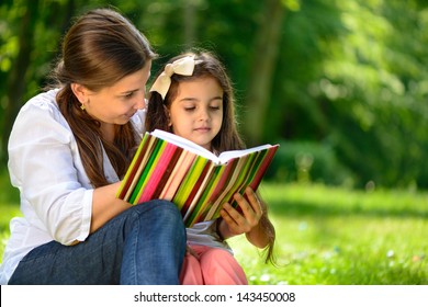 Happy Latino Family Reading Book At Park