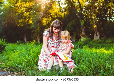 Happy Latino Family Reading Book At Park