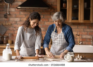 Happy Latino Senior Mother And Grownup Daughter Make Dough Prepare Sweet Pie Or Pastries At Home On Weekend. Smiling Hispanic Mature Mom And Adult Girl Cooking Baking In Kitchen. Hobby Concept.