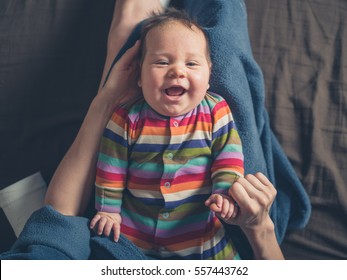 A Happy Laughing Baby Lying In The Lap Of His Mother