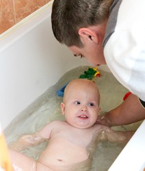 Happy laughing baby taking a bath playing with foam bubbles. Little ...