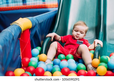 Happy laughing boy 1-2 years old having fun in ball pit in kids amusement park and indoor play center. Child playing with colorful balls in playground ball pool. Activity toys for little kid. - Shutterstock ID 1056590291