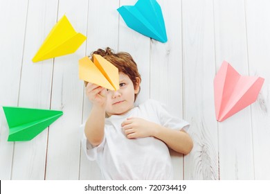 Happy Laughing Child Throwing Paper Airplane Indoors. Happy Childhood, Travel, Vacation Concept. Top View.