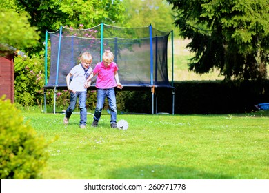 Happy Laughing Children, Twin Teenage Boys, Playing Soccer In The Garden At The Backyard Of The House On Sunny Summer Vacation Day