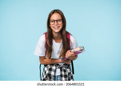 Happy laughing smiling caucasian teenager schoolgirl student pupil holding books and copybooks, getting excellent marks, going back to school isolated in blue background