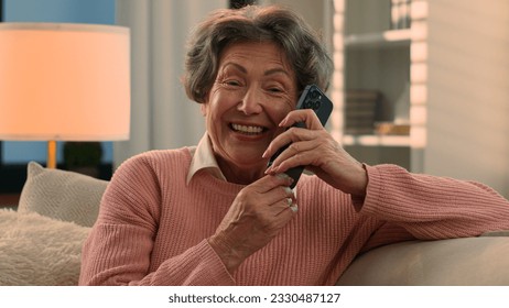 Happy laughing talking phone Caucasian old woman carefree senior lady listening funny news smile laugh retired grandma elderly female grandmother mobile conversation smartphone communication at home - Powered by Shutterstock