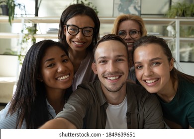 Happy laughing team diverse colleagues posing for selfie portrait in office, friendly group of corporate employees of different age and ethnicities making videocall looking at camera bonding together
