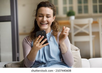 Happy Laughing Young Woman Making Yes Gesture, Looking At Telephone Screen, Reading Message With Online Lottery Win Notification, Celebrating Gambling Auction Success, Getting Sale Discount Code.