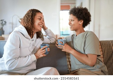 Happy lesbian couple drinking coffee and talking face to face on living room sofa at home - Powered by Shutterstock