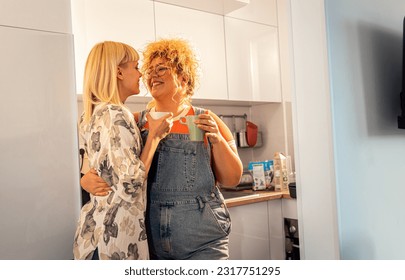 Happy lesbian couple in love spending time together in the kitchen, drinking coffee and enjoying each other's company. - Powered by Shutterstock