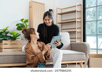 Happy Lesbian Couple Moving into Smart Home, Unpacking Boxes and Using Tablet to Set Up Modern Technology in New House - Powered by Shutterstock