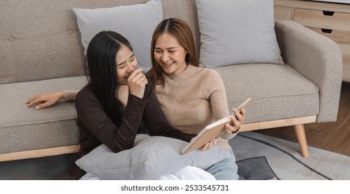 Happy Lesbian Couple Relaxing in Modern Living Room, Reading and Laughing Together on Comfortable Sofa - Powered by Shutterstock