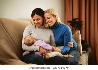 Happy lesbian couple taking care of her small baby at home - LGBT Family and maternity concept - Powered by Shutterstock