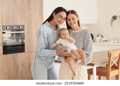 Happy lesbian couple with their little baby in kitchen - Powered by Shutterstock