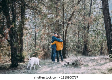 Happy Lesbian Couple Walking In The Forest With A Dog