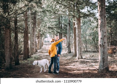 Happy Lesbian Couple Walking In The Forest With A Dog