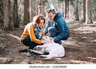 Happy Lesbian Couple Walking In The Forest With A Dog