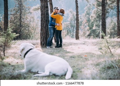 Happy Lesbian Couple Walking In The Forest With A Dog