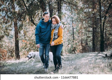 Happy Lesbian Couple Walking In The Forest With A Dog