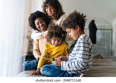 Happy lesbian multiethnic couple in love with childen at home. Family lgbt child happiness concept