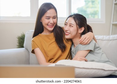 Happy Lesbian, Pleasure Asian Young Two Women, Girl Gay Or Close Friend, Couple Love Embrace, Spending Good Time Together, Using Laptop Computer For Entertainment On Sofa At Home. Activity Of Leisure.