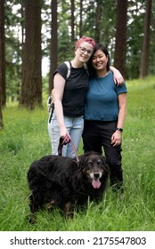 Happy LGBT Couple Hiking With Their Dog In The Woods.