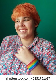 Happy LGBT Female Teen With Red Hair Touching Her Flower Shirt On Green Background. Pride And Diversity Concept.