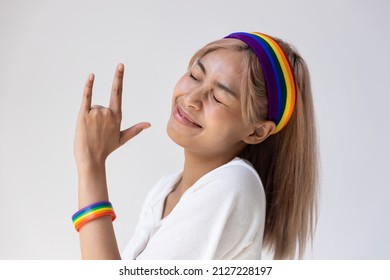 Happy LGBT Woman Wearing LGBTQ Rainbow Headband Showing Love Hand Sign, Concept Of Gay Pride Month, Lesbian Pride, LGBT Awareness Movement, Non-binary Inclusivity And Diversity