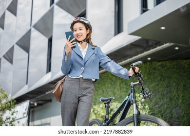 Happy Lifestyle Business Female Commuting Outside In Morning, Asian Smiling Young Woman Use Smart Mobile Phone Talk With Business During Go To Office Work At City Street With Bicycle, Eco Friendly