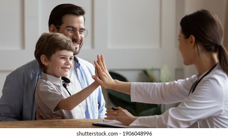 Happy little 7s boy patient with young father give high five to caring female pediatrician after consultation in hospital. Smiling small child greet make deal with woman doctor. Good service concept. - Powered by Shutterstock