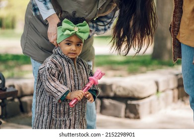 Happy Little African American Baby Girl Walking In A Park. Beautiful Black Little Girl Laughing And Playing Outside. Mother Fixing Girls Hair.