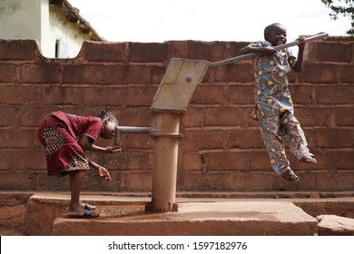 Happy Little African Boy Pumping Water For His Sister