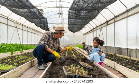 Happy little African child girl learning to grow organic vegetable with farmer in greenhouse garden. Student study agriculture subject gardening healthy food for sustainable living at agriculture farm - Powered by Shutterstock