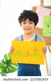 Happy Little Asian Boy Showing His Painting - Drawing Art On A Paper To Camera. Education And Development In The Elementary Or Preschool Age Concept. Kindergarten Children Portrait.