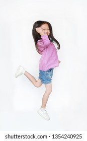 Happy Little Asian Child Girl Jumping In Air On White Background. Full Length Side View Of Smiling Kid Concept.