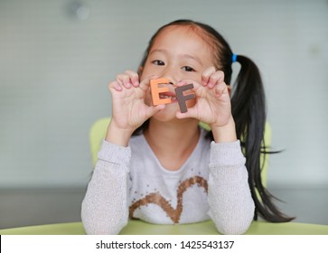 Happy Little Asian Child Girl Holding Alphabet EF (Executive Functions) Text On Her Face. Education And Development Concept.