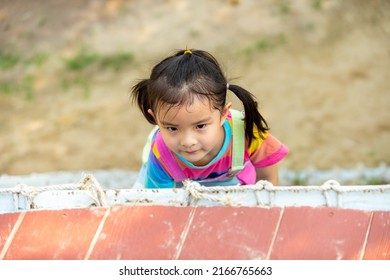 Happy Little Asian Child Girl Climbing And Playing At Playground In The Park On Summer Vacation. Children Kid Enjoy And Fun Outdoor Activity. Kindergarten Kid Outdoor Exercising And Playing At Park.