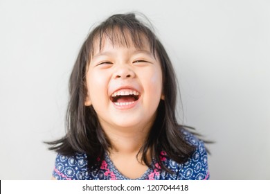 Happy Little asian girl child showing front teeth with big smile and laughing: Healthy happy funny smiling face young adorable lovely female kid.Joyful portrait of asian elementary school student.