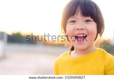 Happy Little asian girl child showing front teeth with big smile and laughing: Healthy happy funny smiling face young adorable lovely female kid.Joyful portrait of asian elementary school student. 