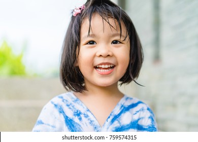Happy Little Asian Girl Having Fun At The Park.Little Asian Girl Child Showing Front Teeth With Big Smile.Healthy Happy Funny Smiling Face Child.Joyful Portrait Of Asian Elementary School Student.