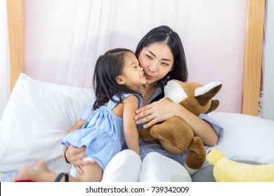 Happy little asian girl kissing her mother in house - Shutterstock ID 739342009