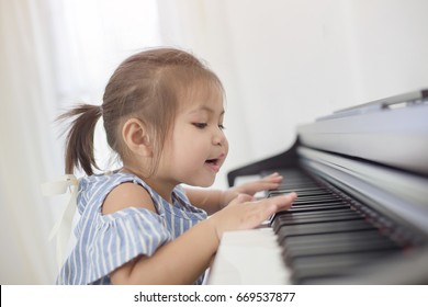 Happy Little Asian Girl Playing Piano At Home