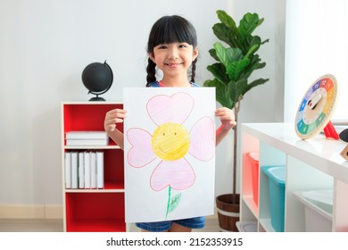 Happy Little Asian Girl Showing Her Painting - Drawing Art On A Paper To Camera. Education And Development In The Elementary Or Preschool Age Concept. Kindergarten Children Portrait.